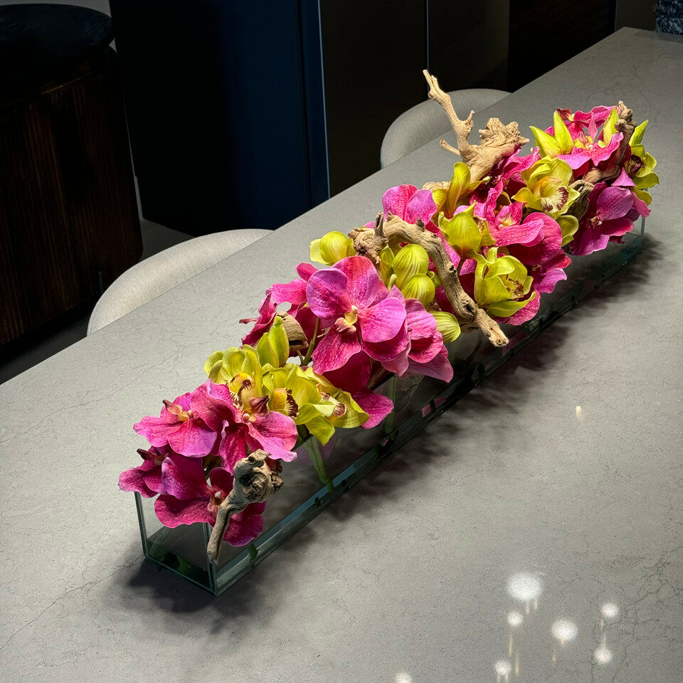Moderne Hausvase aus Glas mit rosa Vanda-Orchidee und grünen Cymbidien