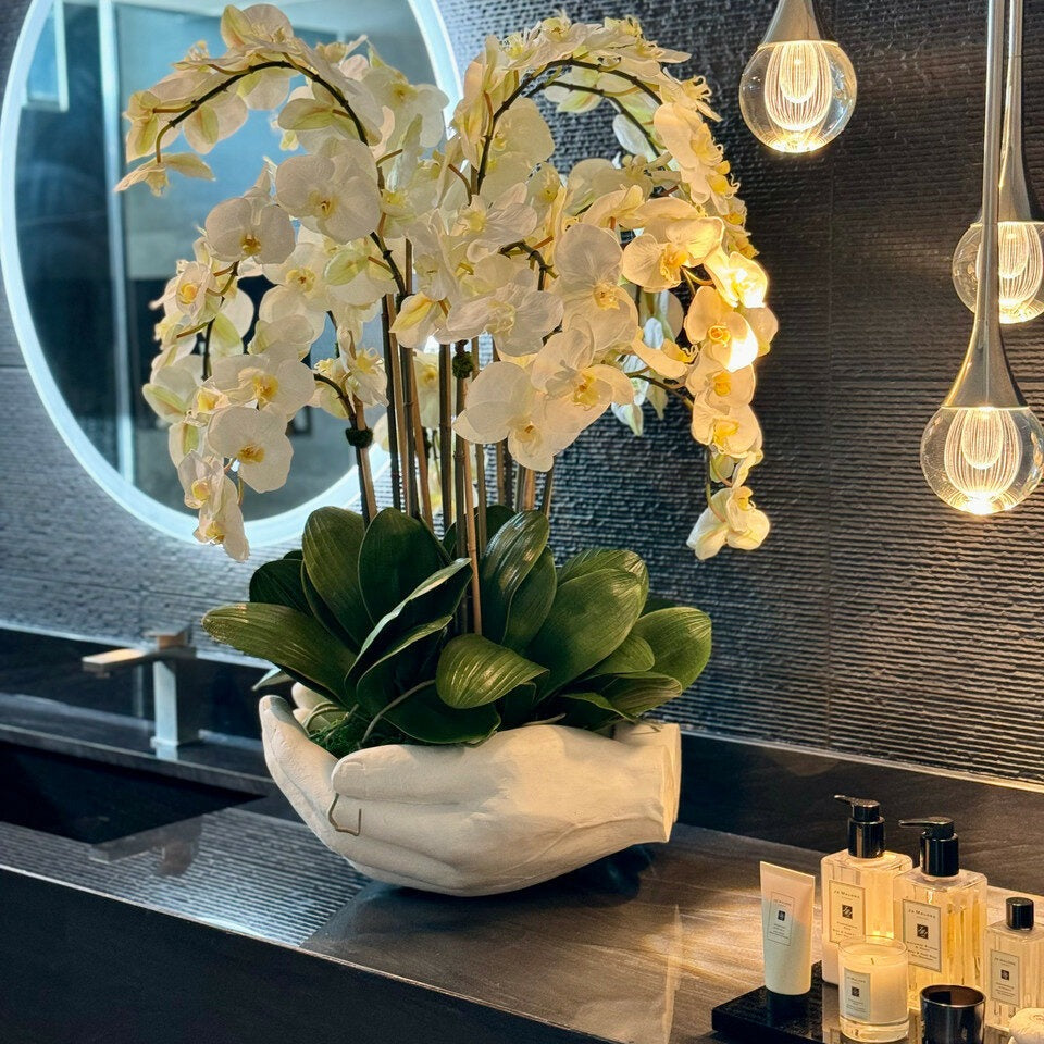 Weißer Phalaenopsis-Orchideenstrauß in Blumenvase mit Skulptur "Offene Hände"