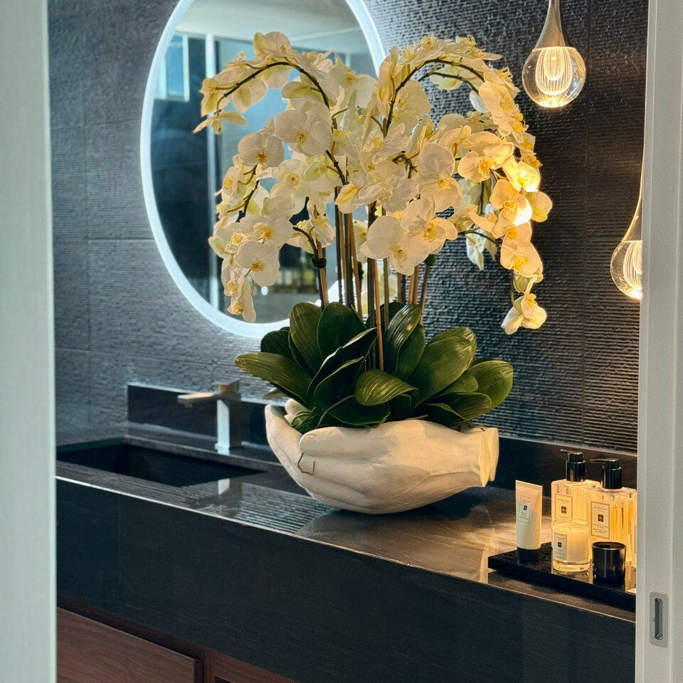 Weißer Phalaenopsis-Orchideenstrauß in Blumenvase mit Skulptur "Offene Hände"